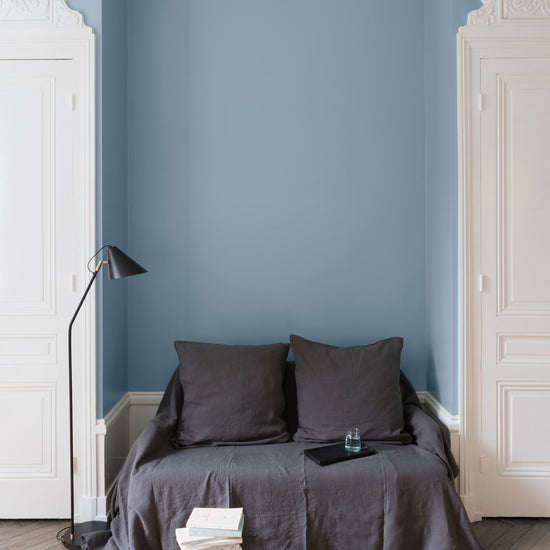 Salon aux murs bleus, peinture Velours de Peinture Bleu Horizon Libéron avec portes blanches et textiles gris.