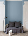 Salon aux murs Bleu Horizon Libéron, avec canapé gris, portes blanches, lampadaire noir et parquet clair.
