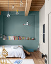 Chambre d'enfant aux murs bleus, peinture Velours de Peinture Bleu Neptune Libéron, avec poutres en bois au plafond et étagères de livres.