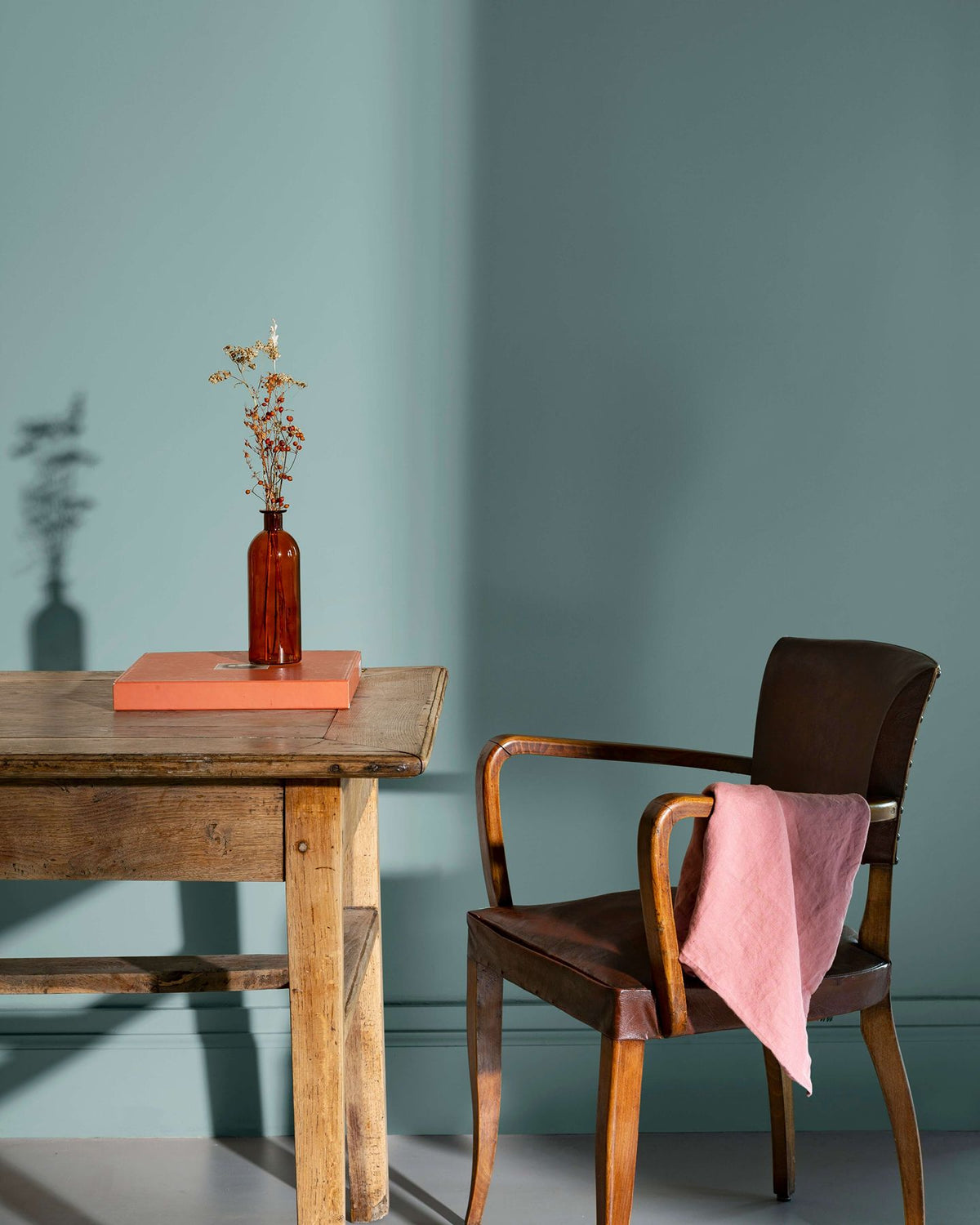 Coin de bureau avec une table rustique en bois, une chaise en cuir et des murs peints avec la peinture Libéron Velours de Peinture, teinte Bleu Neptune