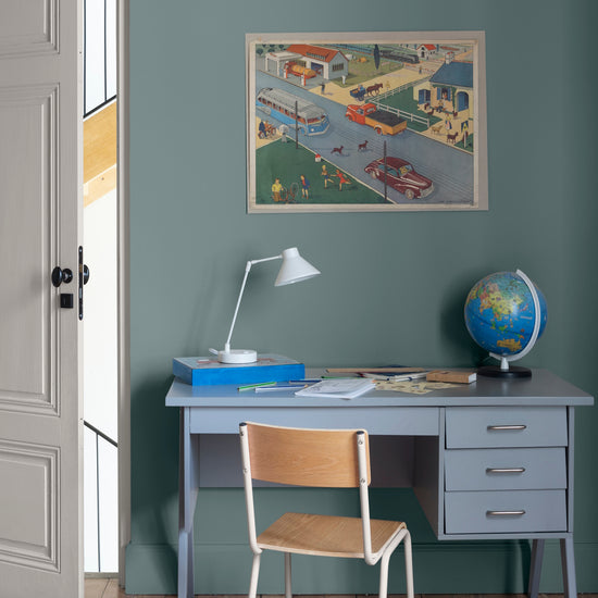 Chambre aux murs bleu Neptune, Velours de Peinture Libéron, avec bureau bleu, chaise en bois, globe et affiche vintage.
