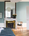 Chambre aux murs bleu Neptune, Velours de Peinture Libéron, avec cheminée en marbre, miroir et chaise en bois.