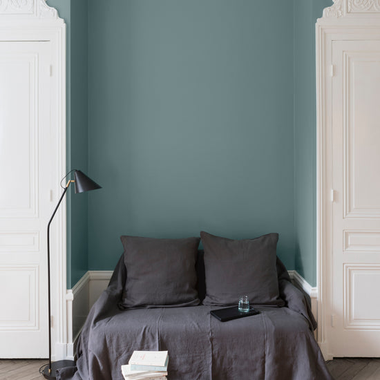 Salon aux murs bleu Neptune Libéron, avec canapé gris, portes blanches, lampadaire noir et parquet clair.