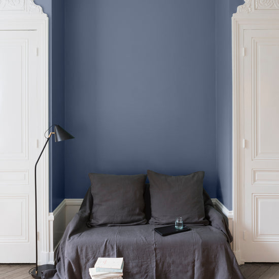 Salon aux murs bleus, peinture Velours de Peinture Bleu Panicaut Libéron avec portes blanches et textiles gris.