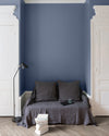 Salon aux murs Bleu Panicaut Libéron, avec canapé gris, portes blanches, lampadaire noir et parquet clair.