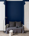 Salon aux murs Bleu Vintimille Libéron, avec canapé gris, portes blanches, lampadaire noir et parquet clair.