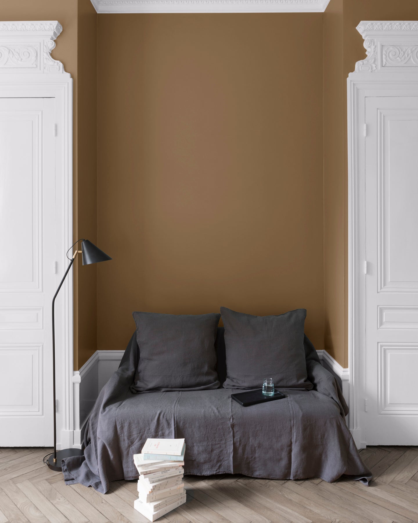 Salon aux murs Bronze Astrolabe, Velours de Peinture Libéron, avec canapé gris, portes blanches et parquet clair.
