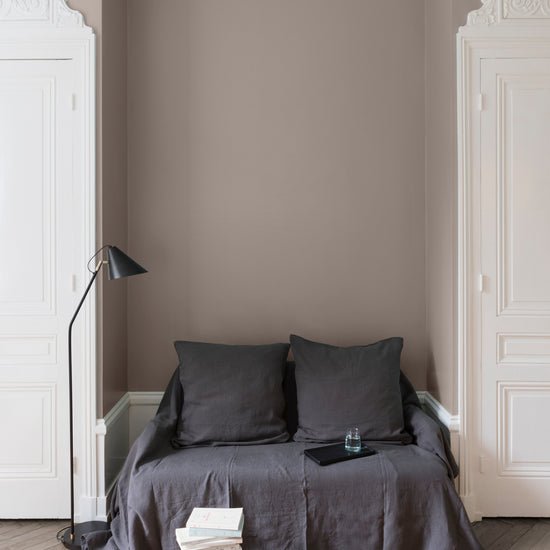 Salon aux murs Brun Eiffel Velours de Peinture Libéron, avec canapé gris, portes blanches, lampadaire noir et parquet clair.