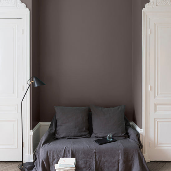 Salon aux murs bruns, peinture Velours de Peinture Brun Minier Libéron avec portes blanches et textiles gris.
