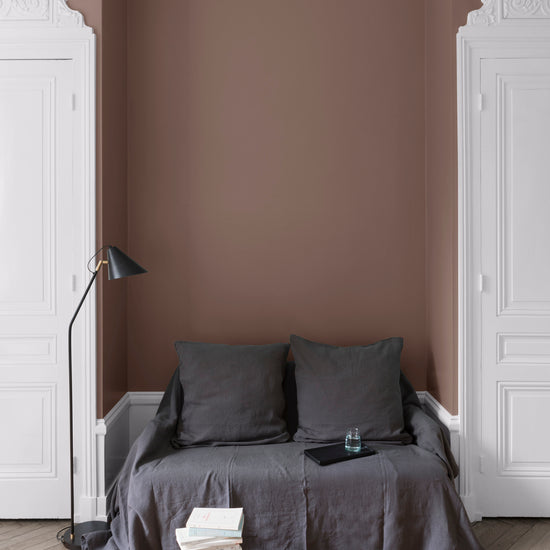 Salon aux murs bruns, peinture Velours de Peinture Brun Puce Royale Libéron avec portes blanches et textiles gris.