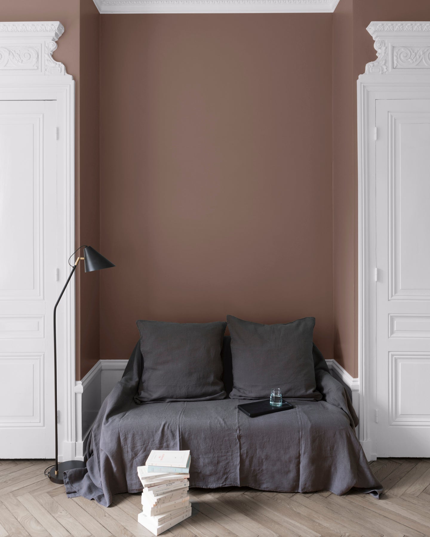 Salon aux murs Brun Puce Royale Velours de Peinture Libéron, avec canapé gris, portes blanches, lampadaire noir et parquet clair.