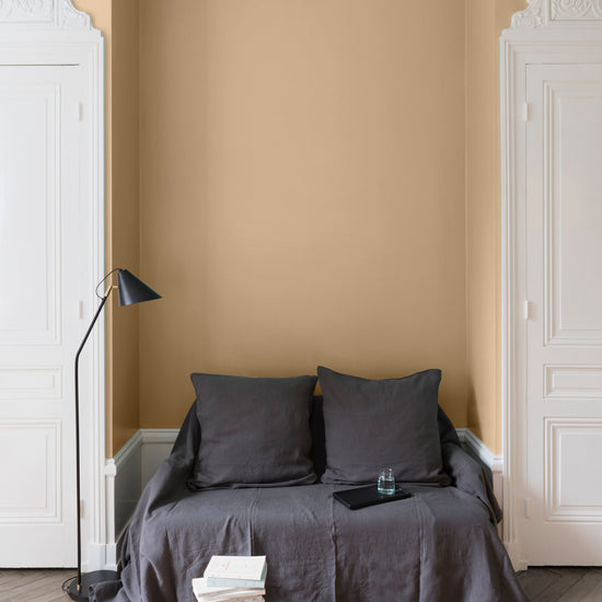 Salon aux murs Confiture de Lait, Velours de Peinture Libéron, avec canapé gris, portes blanches et parquet clair.