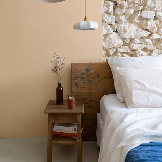 Chambre aux murs confiture de lait, Velours de Peinture Libéron, avec tête de lit en bois et linge blanc.