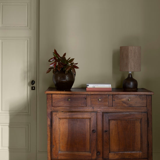 Pièce avec murs verts, peinture Velours de Peinture Crème d'Artichaut Libéron, avec porte verte, commode en bois et parquet