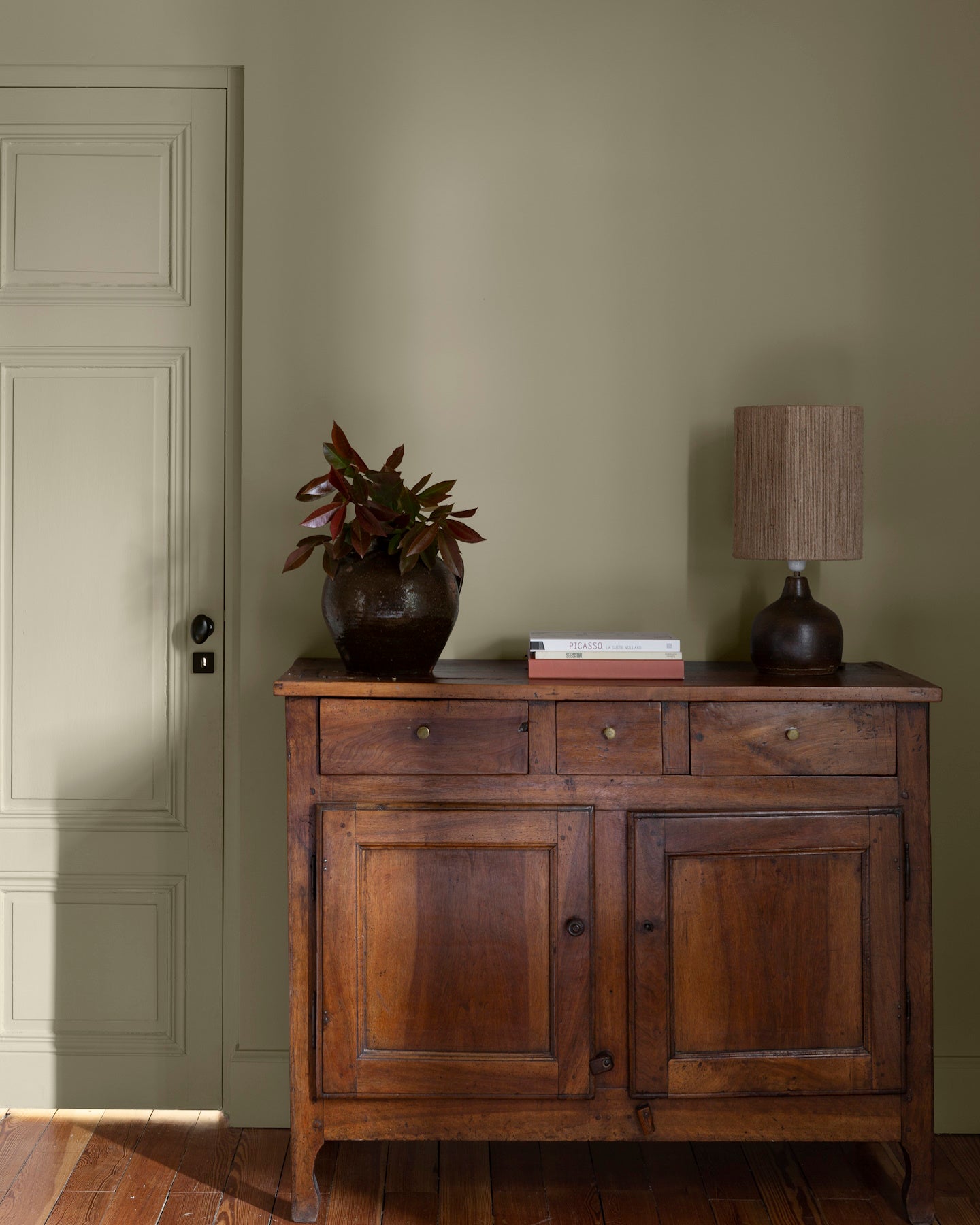 Pièce avec murs verts, peinture Velours de Peinture Crème d'Artichaut Libéron, avec porte verte, commode en bois et parquet