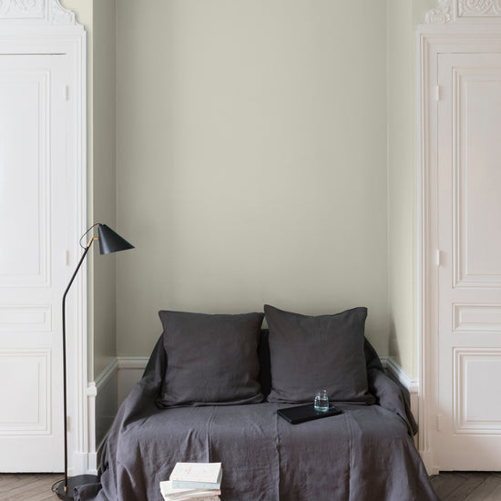 Salon aux murs blancs, peinture Velours de Peinture Écru Brut Libéron avec portes blanches et textiles gris.