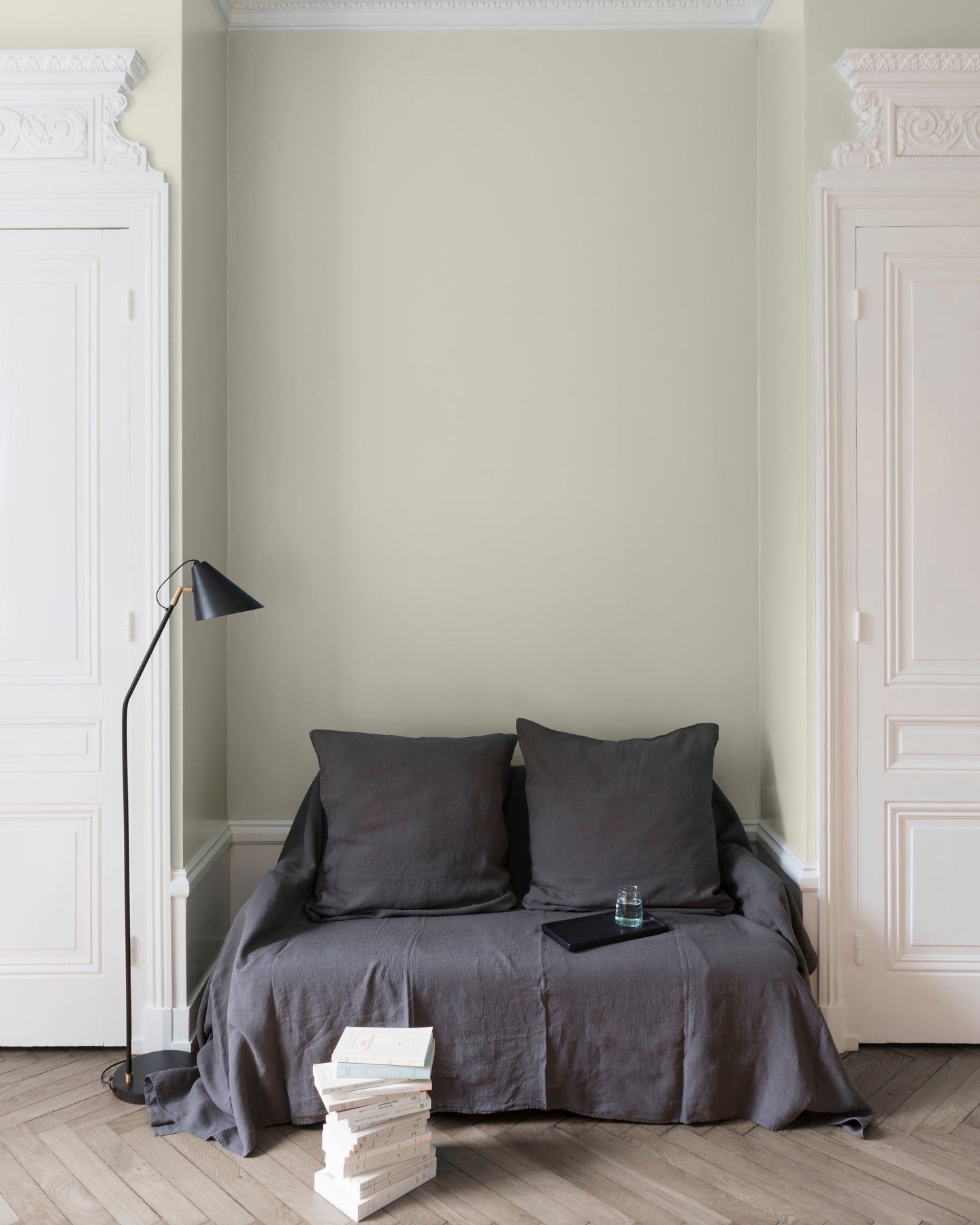 Salon aux murs blancs, peinture Velours de Peinture Écru Brut Libéron avec portes blanches et textiles gris.