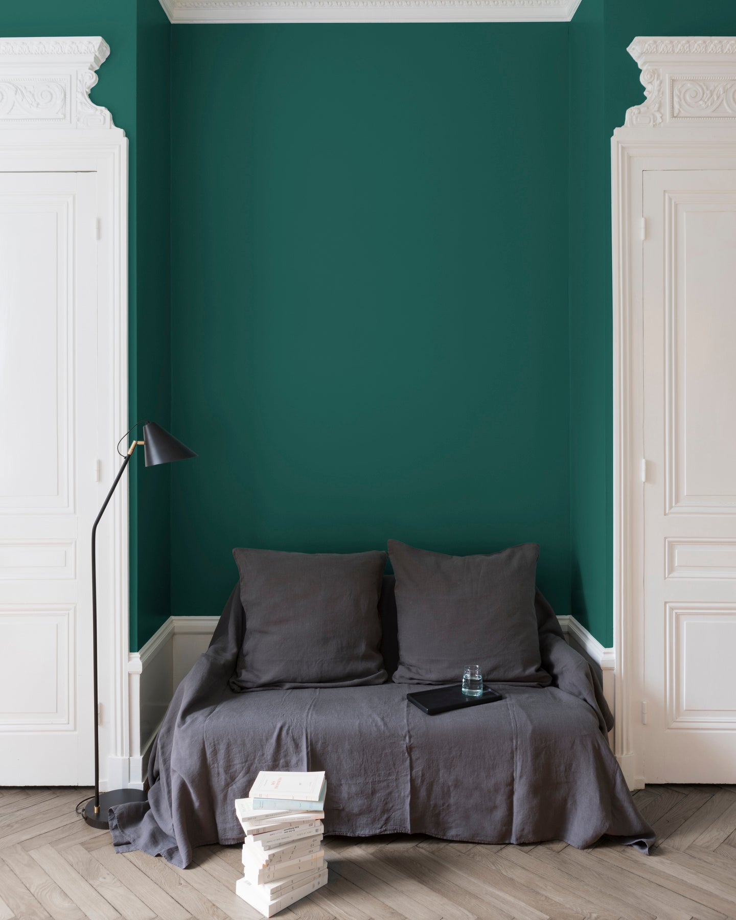 Salon aux murs Feuille d'Acanthe Velours de Peinture Libéron, avec canapé gris, portes blanches, lampadaire noir et parquet clair.