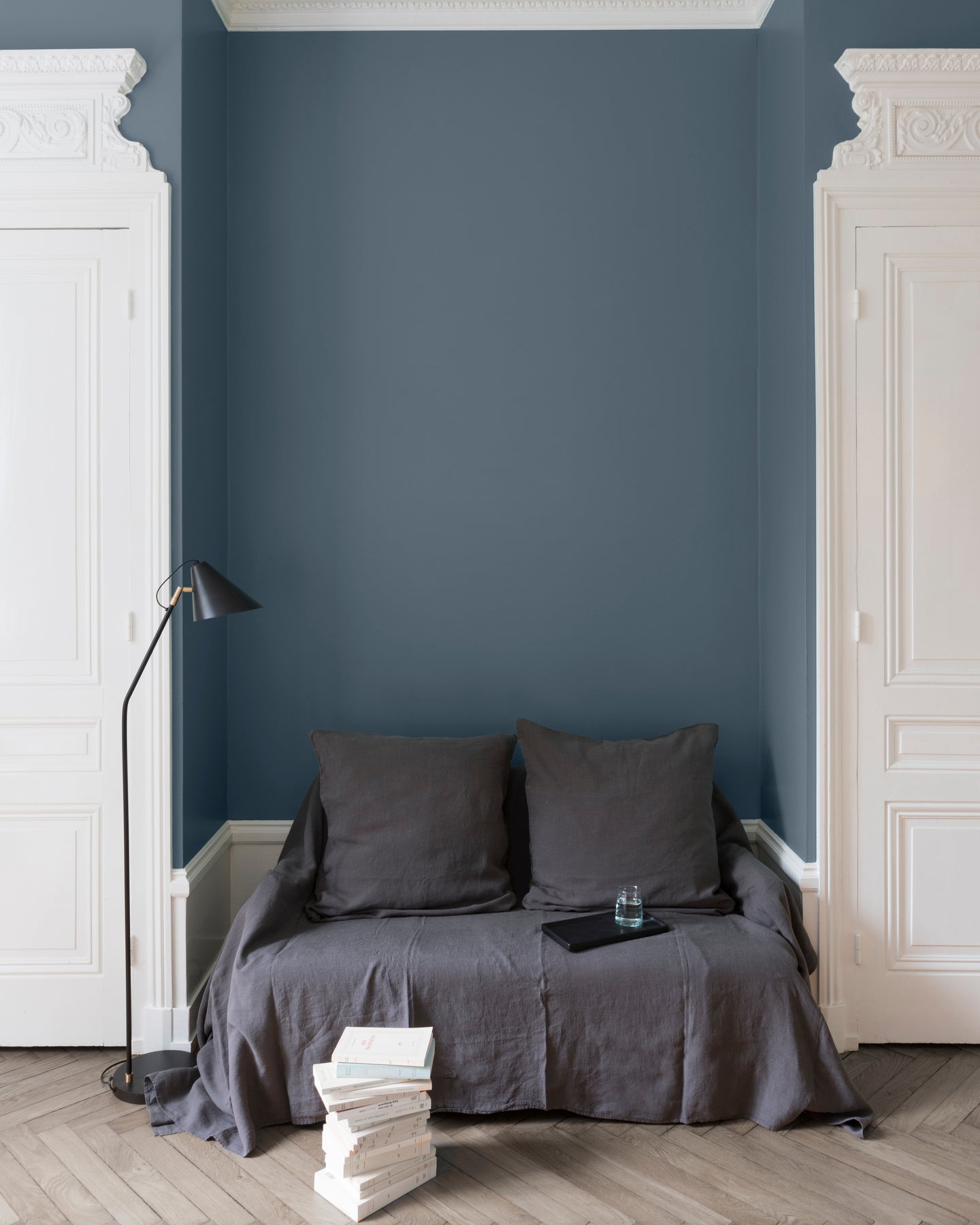 Salon aux murs bleus, peinture Velours de Peinture Fine de Claire Libéron avec portes blanches et textiles gris.