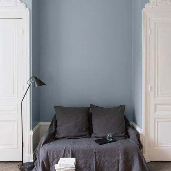 Salon aux murs bleus, peinture Velours de Peinture Fleur de Lin Libéron avec portes blanches et textiles gris.