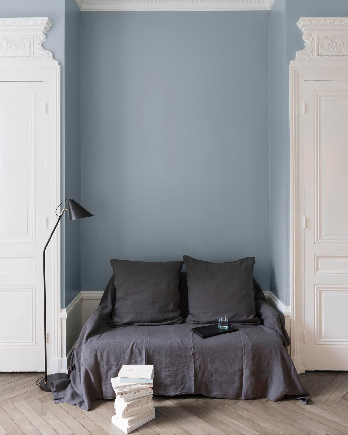 Salon aux murs Fleur de Line Velours de Peinture Libéron, avec canapé gris, portes blanches, lampadaire noir et parquet clair.