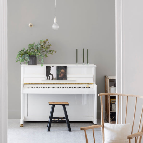 Pièce à vivre lumineuse avec murs blancs, peinture Velours de Peinture Grège Cairn Libéron, piano blanc et chaise en bois