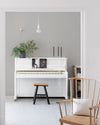 Pièce à vivre lumineuse avec murs blancs, peinture Velours de Peinture Grège Cairn Libéron, piano blanc et chaise en bois