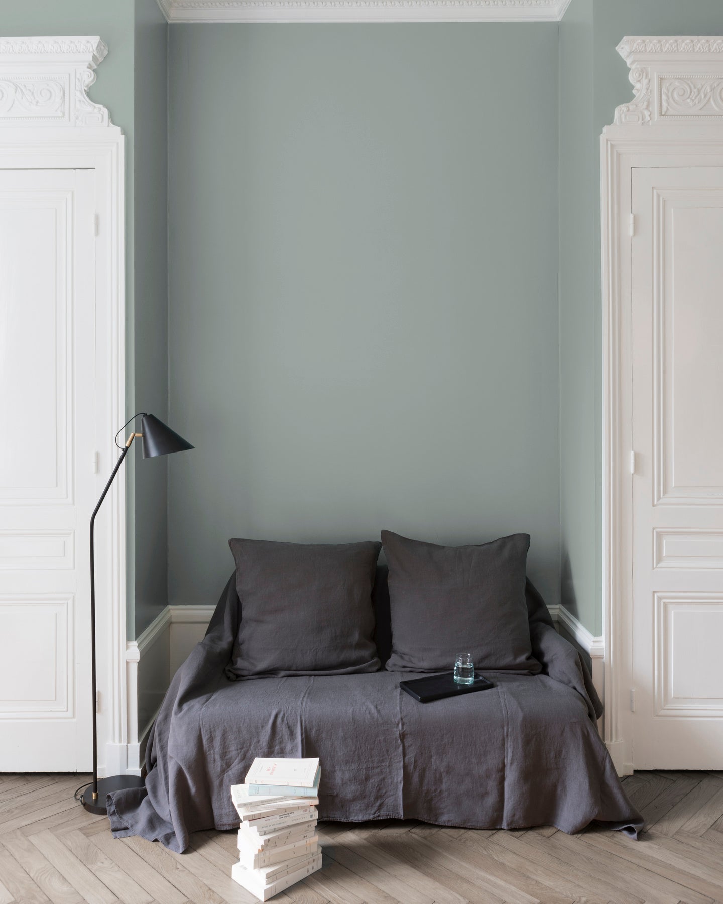 Salon aux murs Grès Gris Velours de Peinture Libéron, avec canapé gris, portes blanches et parquet clair.