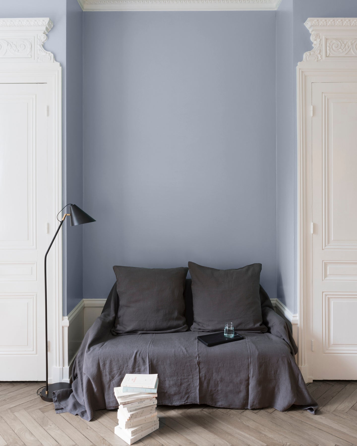 Salon aux murs bleus, peinture Velours de Peinture Gris Bleu Guimet Libéron avec portes blanches et textiles gris.