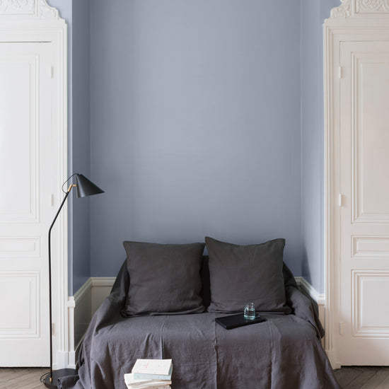 Salon aux murs Bleu Guimet, Velours de Peinture Libéron, avec canapé gris, portes blanches et parquet clair.