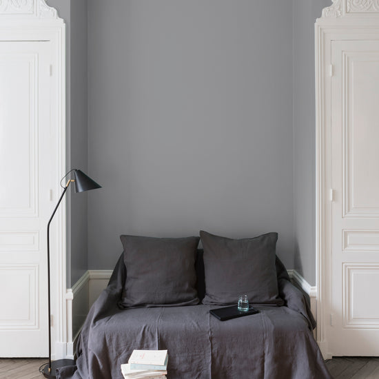 Salon aux murs Gris Corne de Brume Velours de Peinture Libéron, avec canapé gris, portes blanches, lampadaire noir et parquet clair.