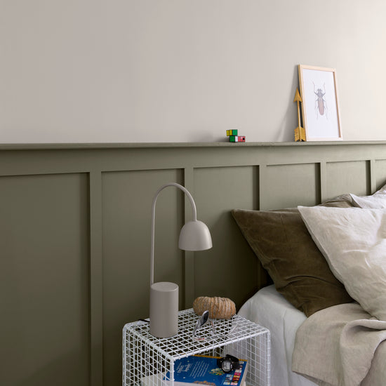 Chambre aux murs crème topinambour et gris gavroche Libéron, avec tête de lit peinte, linge beige et lampe grise.