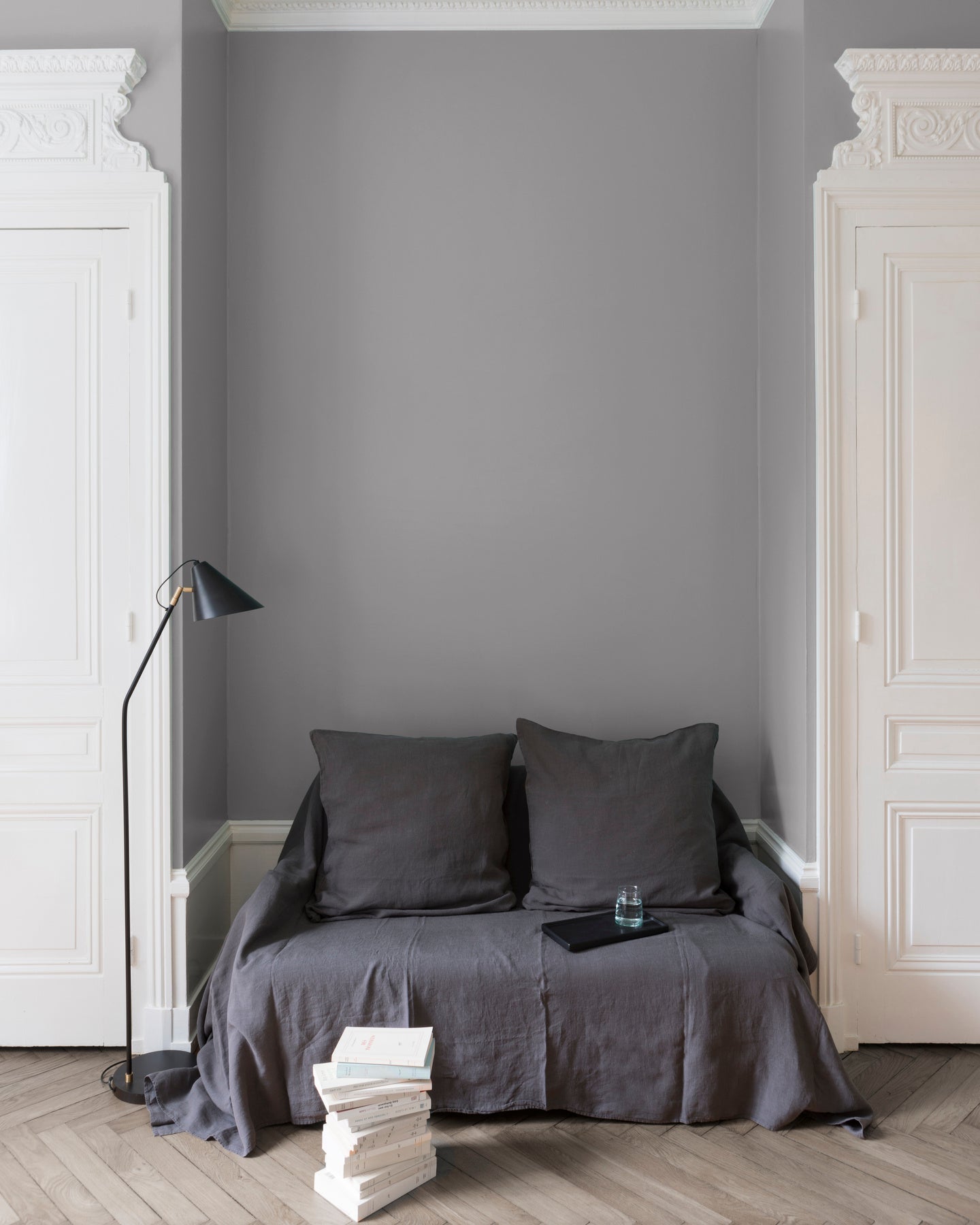 Salon aux murs Gris Jolie Brise, Velours de Peinture Libéron, avec canapé gris, portes blanches et parquet clair.