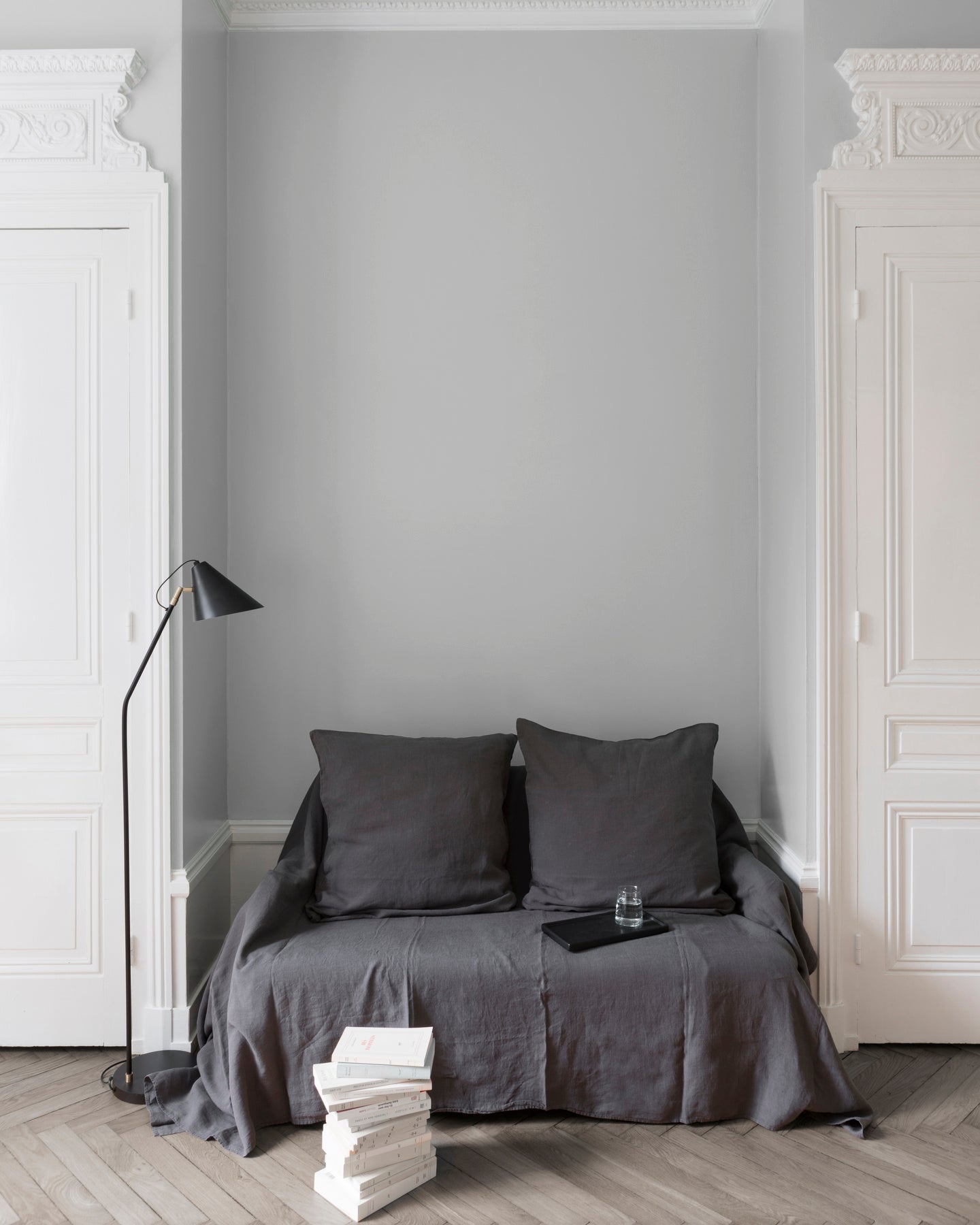 Salon aux murs Gris Sarrazin, Velours de Peinture Libéron, avec canapé gris, portes blanches et parquet clair.