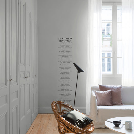 Salon lumineux avec murs et portes de placards gris, peinture Velours de Peinture Gris Temps de Pluie Libéron, avec rideaux blancs, canapé gris et fauteuil en rotin