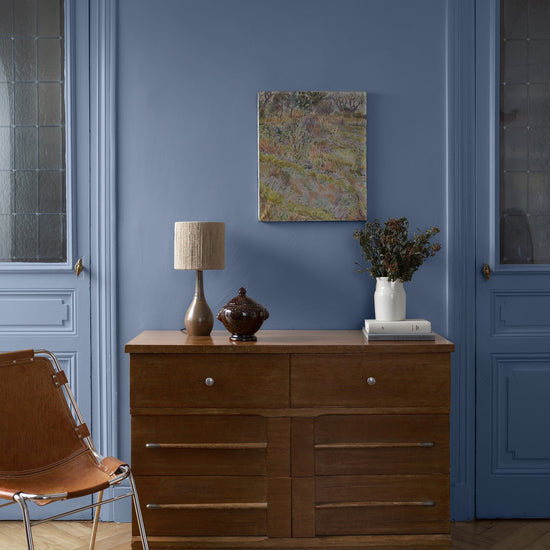 Pièce à vivre avec murs bleus, peinture Velours de Peinture Heure Bleue Libéron, commode en bois et chaise marron