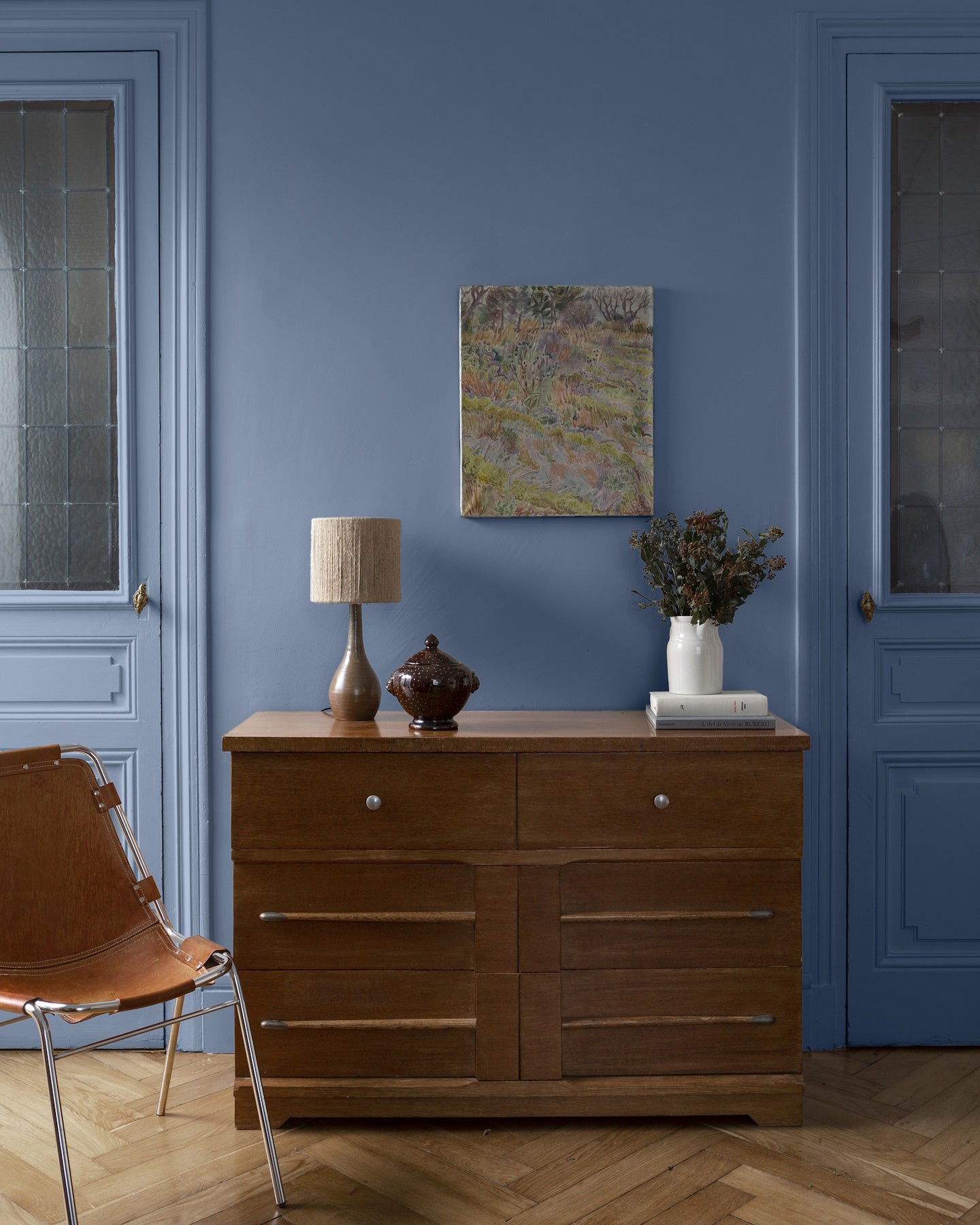 Pièce à vivre avec murs bleus, peinture Velours de Peinture Heure Bleue Libéron, commode en bois et chaise marron
