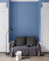 Salon aux murs Heure Bleue, Velours de Peinture Libéron, avec canapé gris, portes blanches et parquet clair.