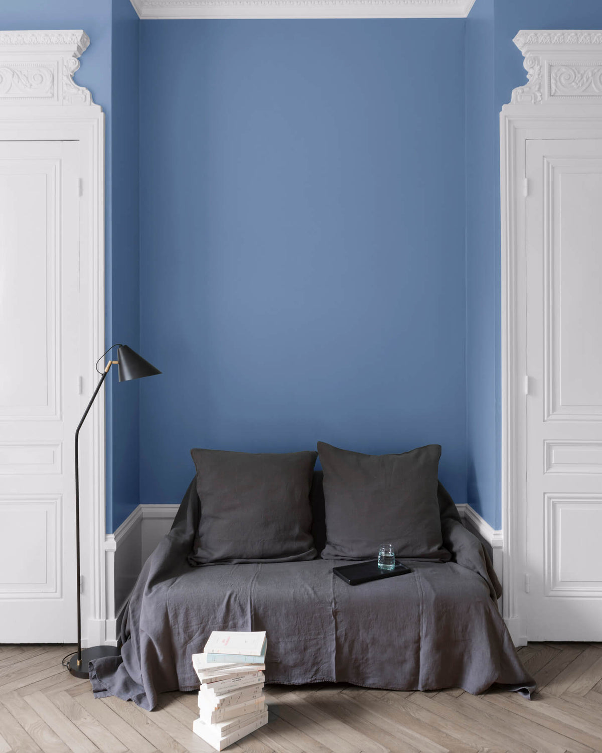 Salon aux murs Heure Bleue, Velours de Peinture Libéron, avec canapé gris, portes blanches et parquet clair.