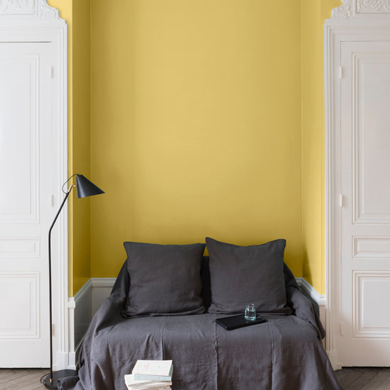 Salon aux murs Jaune de Menton, Velours de Peinture Libéron, avec canapé gris, portes blanches et parquet clair.