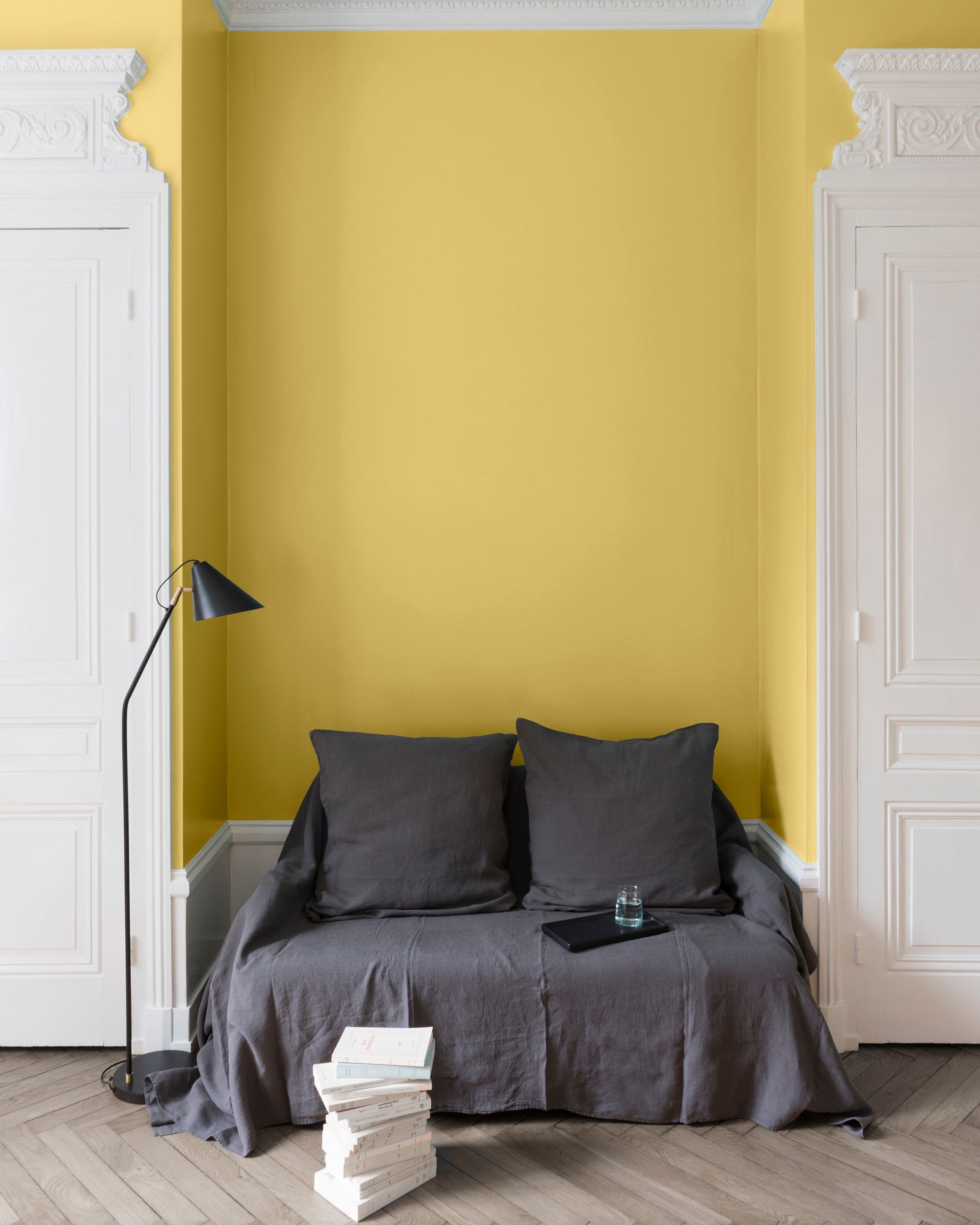Salon aux murs Jaune de Menton, Velours de Peinture Libéron, avec canapé gris, portes blanches et parquet clair.