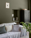 Salon ambiance chaleureuse aux murs verts, peinture Velours de Peinture Kaki Barda Libéron, avec canapé gris et bouquet de fleurs
