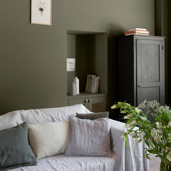 Salon ambiance chaleureuse aux murs verts, peinture Velours de Peinture Kaki Barda Libéron, avec canapé gris et bouquet de fleurs