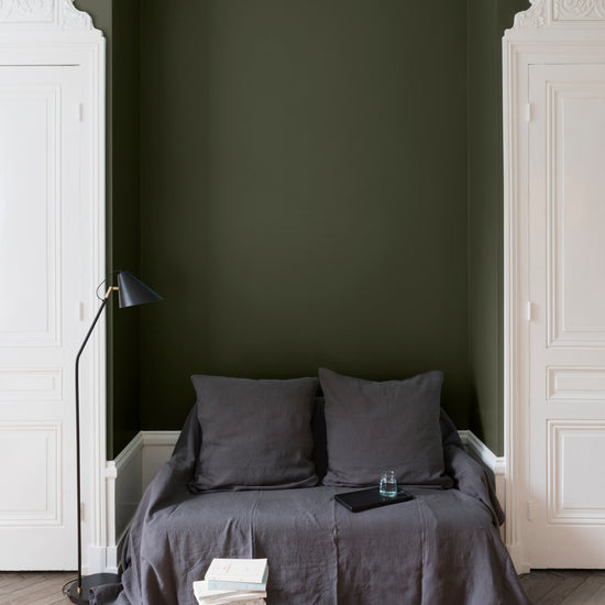 Salon aux murs kaki barda Libéron, avec canapé gris, portes blanches, lampadaire noir et parquet clair.