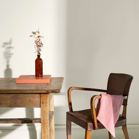 Coin de bureau avec une table rustique en bois, une chaise en cuir et des murs peints avec la peinture Libéron Velours de Peinture, teinte Monnaie du Pape.