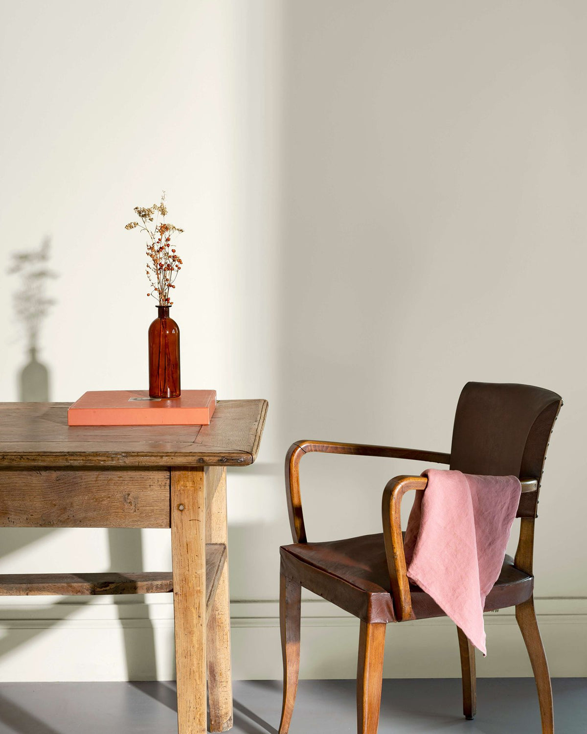 Coin de bureau avec une table rustique en bois, une chaise en cuir et des murs peints avec la peinture Libéron Velours de Peinture, teinte Monnaie du Pape.