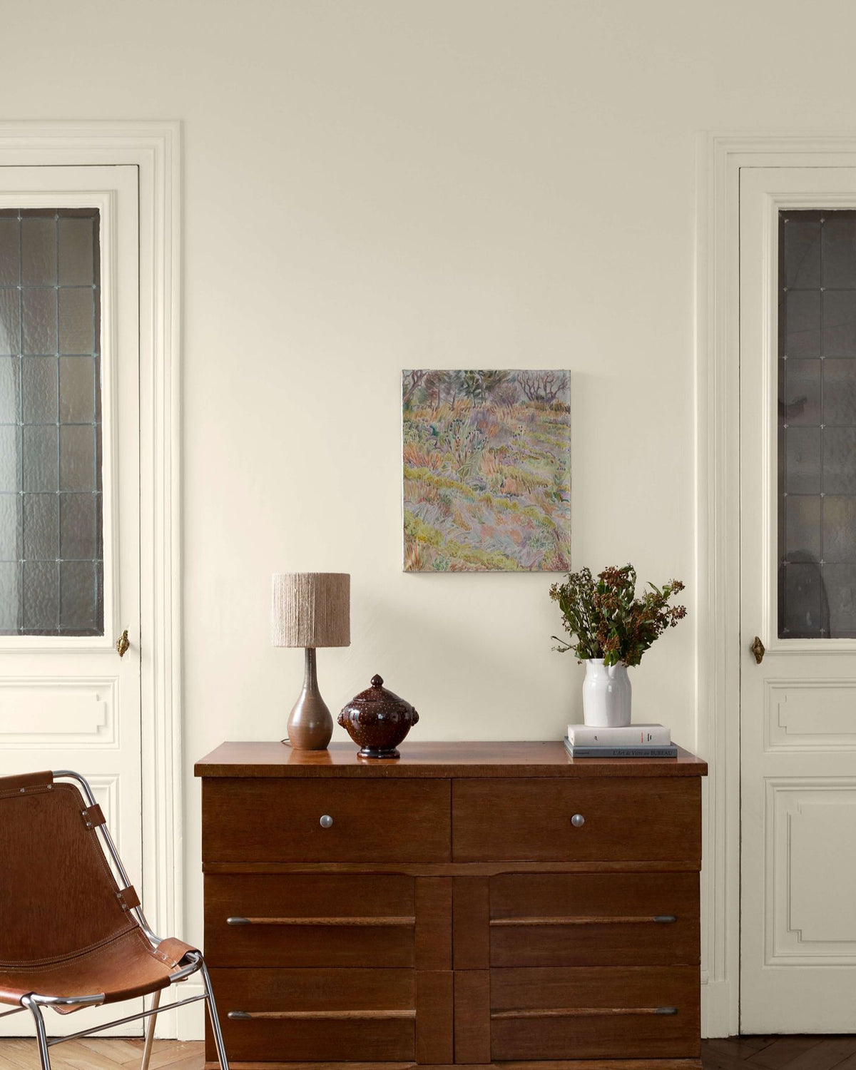 Salon avec une commode en bois, des murs et des portes peintes avec la peinture Libéron Velours de Peinture, teinte Monnaie du Pape.