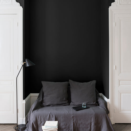 Salon aux murs noirs, peinture Velours de Peinture Noir Smoking Libéron avec portes blanches et textiles gris.