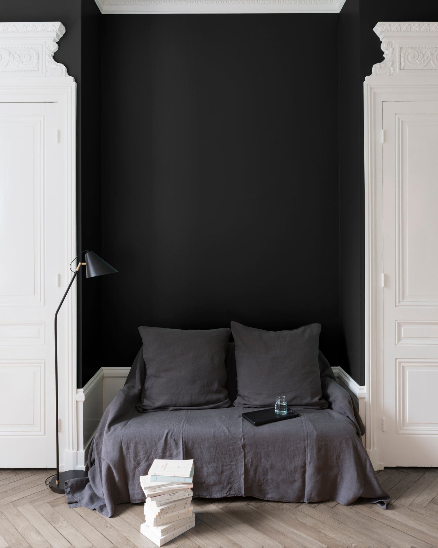 Salon aux murs noirs, peinture Velours de Peinture Noir Smoking Libéron avec portes blanches et textiles gris.