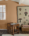 Coin enfant aux murs ocre de Broux Libéron, avec pupitre en bois, porte vitrée et grand tapis illustré.